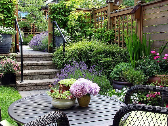 Garden patio with outdoor seating, surrounded by lush greenery and colorful flowers