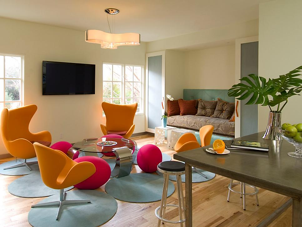 Colorful modern living room with bright orange and pink chairs, a cozy seating nook, and natural light