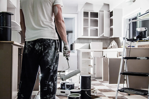 Renovation in progress with painter holding roller in a kitchen under construction